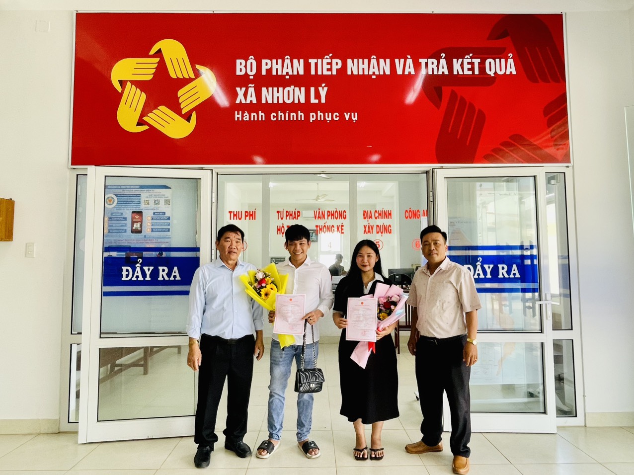 Ông Nguyễn Tấn Dũng - Chủ tịch UBND xã Nhơn lý (ngoài cùng bên trái) tặng hoa chúc mừng cho cặp đôi nhận kết quả Đăng ký kết hôn năm 2024